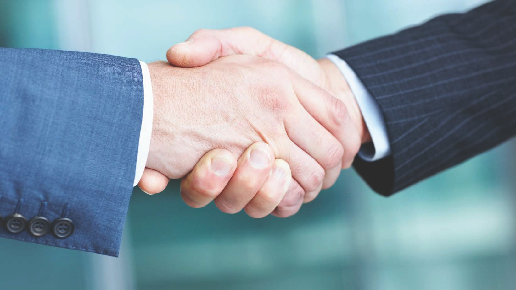 A close-up of a handshake of people wearing business suits. 